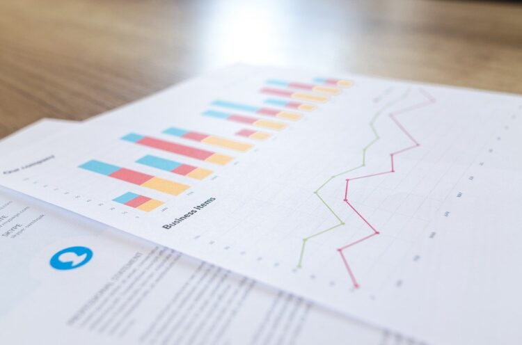 Bar and line graphs on printed business reports placed on a wooden desk.