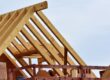 Timber roof trusses and framing under construction against a clear sky.