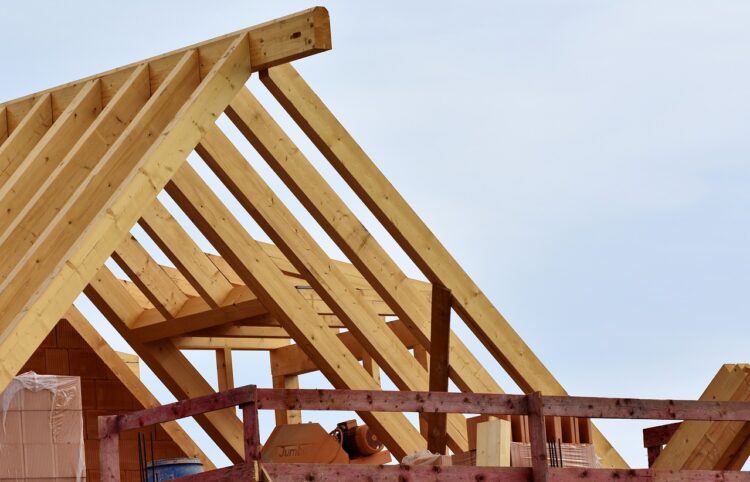 Timber roof trusses and framing under construction against a clear sky.
